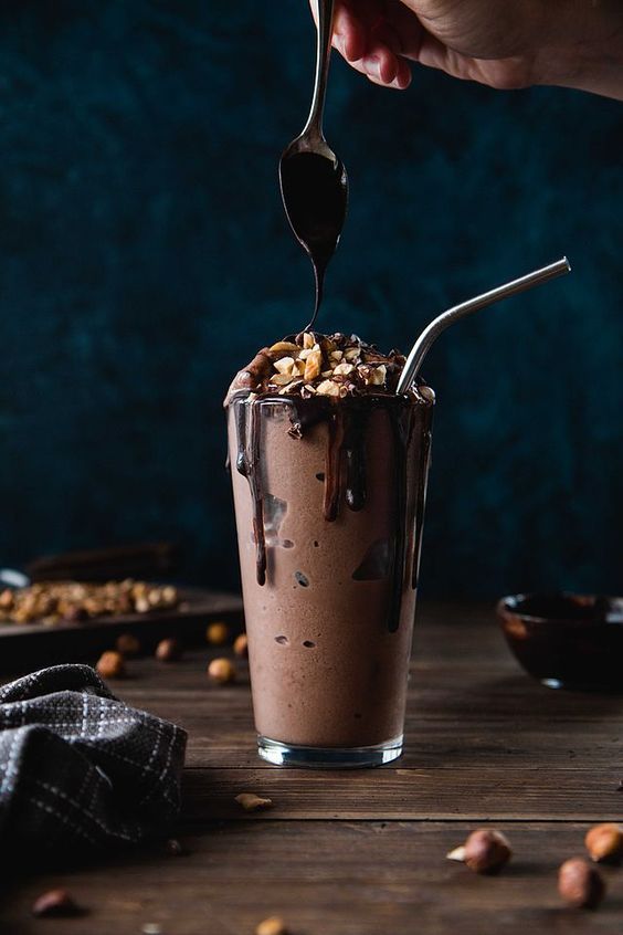 A tall glass of Velvet Drip thick chocolate shake with chocolate sauce dripping down the side, set against a dark background